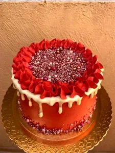 Bolo na cor vermelha com decoração de perolas nas cores brancs, douradas e rosas,